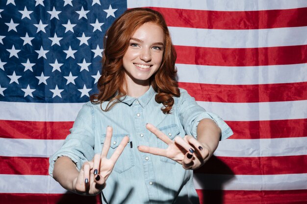 Cheerful redhead young lady showing peace gesture.