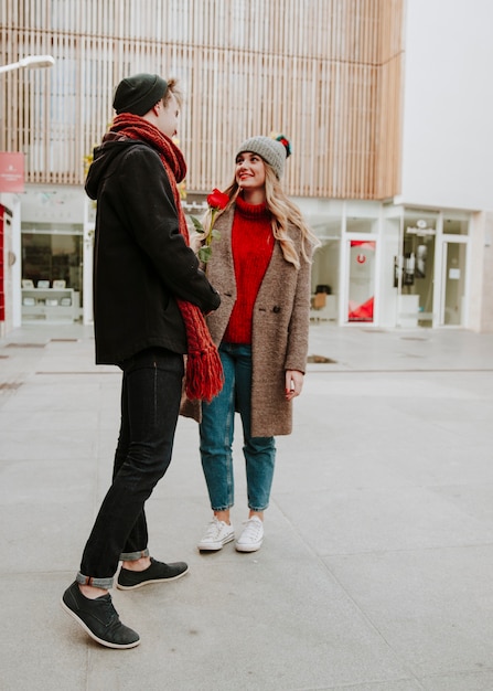 Cheerful romantic man giving rose to woman