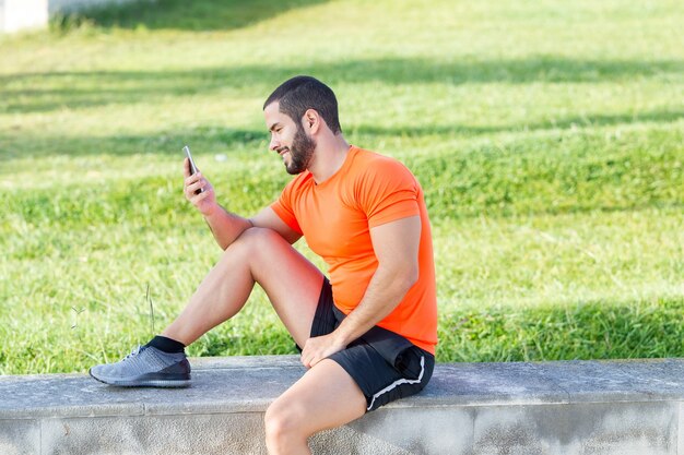 Cheerful runner using phone to analyze his results