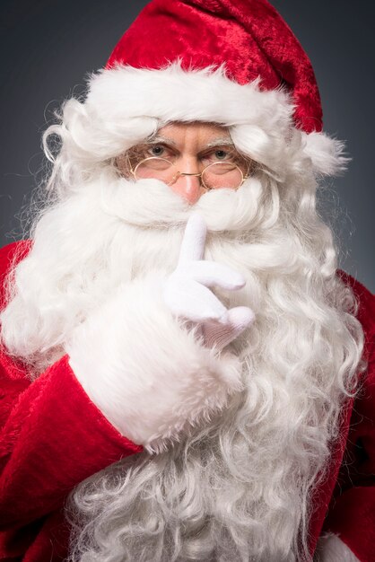 Cheerful santa claus showing a silence sign