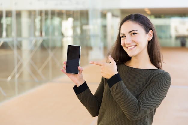 Cheerful satisfied cellphone user introducing new online app