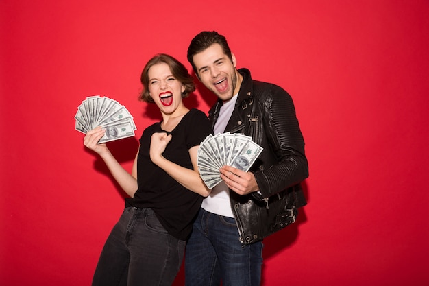 Cheerful screaming punk couple holding money and looking