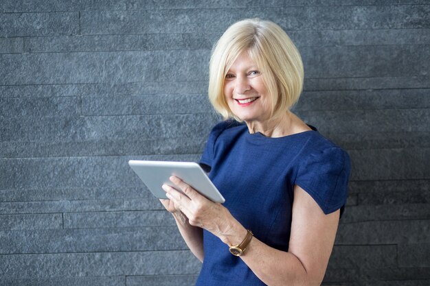 Cheerful senior business lady using tablet