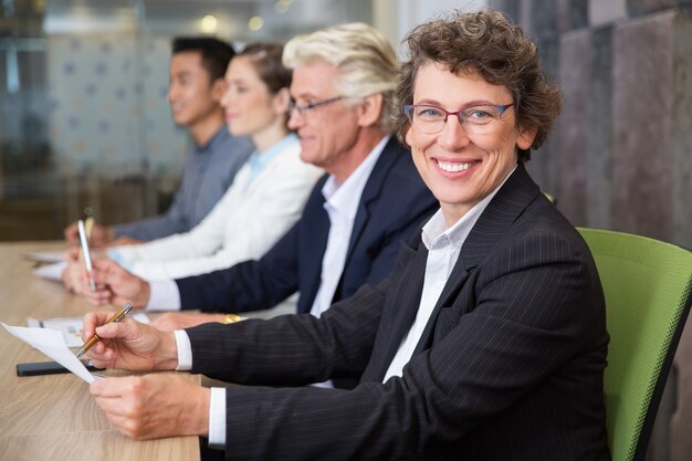 Cheerful senior businesswoman sitting at meeting