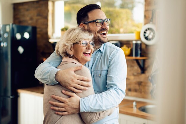 Cheerful senior woman embracing her mid adult son who came to visit her at home