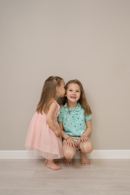 Free photo cheerful sisters moments on beige background