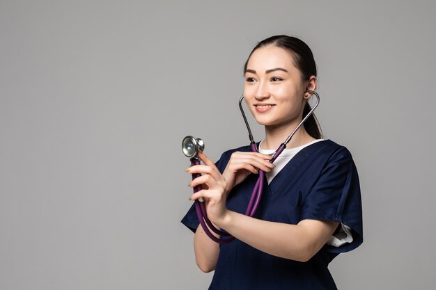 Free Photo cheerful smiling asian female doctor examing with stethoscope, isolated over white wall