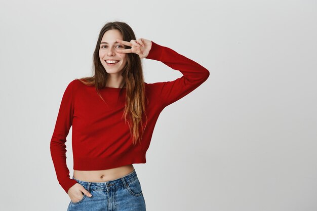 Cheerful smiling, attractive woman in cropped top show peace sign