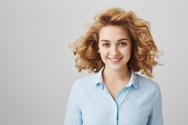 Cheerful smiling curly-haired female employee looking confident