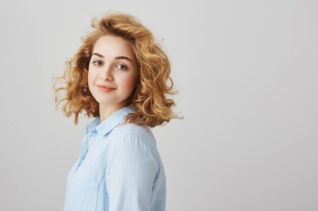 Cheerful smiling curly-haired female employee looking confident