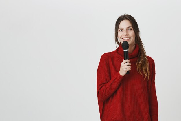 Cheerful smiling girl talking in microphone