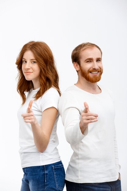Cheerful smiling redhead man, woman point at front