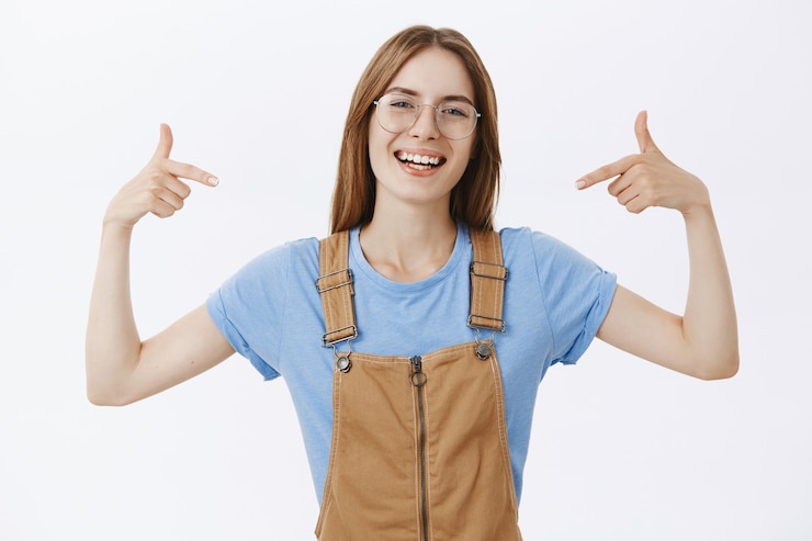 Free Photo cheerful smiling woman in glasses pointing at herself or logo
