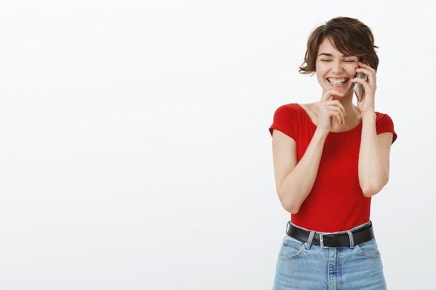 Бесплатное фото Веселая улыбающаяся женщина смеется, разговаривает по мобильному телефону счастлива