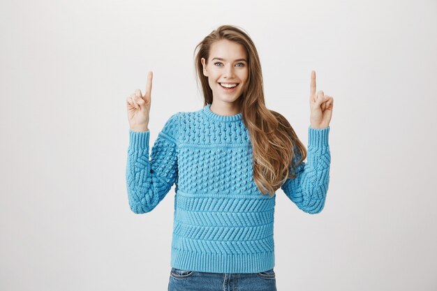 Cheerful smiling woman pointing fingers up