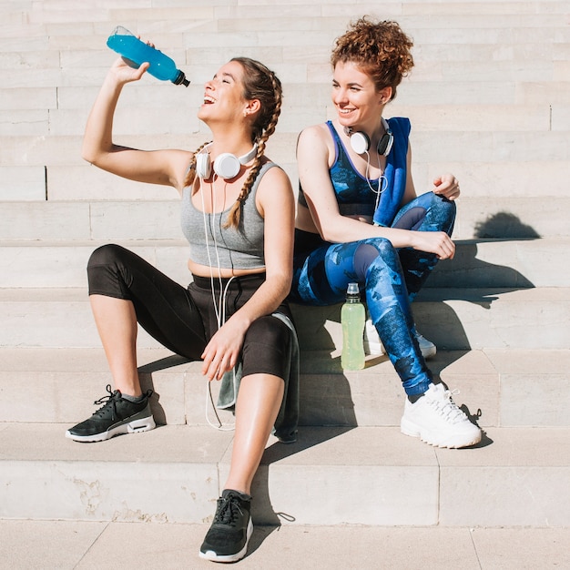 Cheerful sportive girlfriends chilling in sunlight