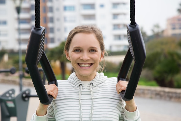 陽気なスポーティな女の子が屋外のジム用品でポーズ