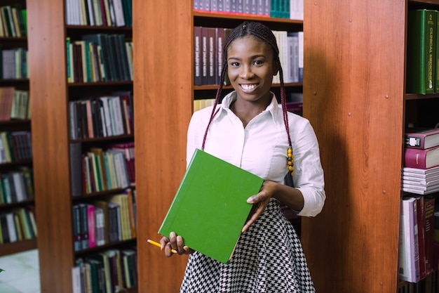 Cheerful student holding heavy textbook