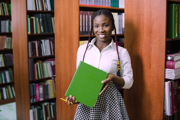 Cheerful student holding heavy textbook