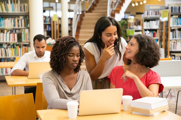 Cheerful students working over new project at library