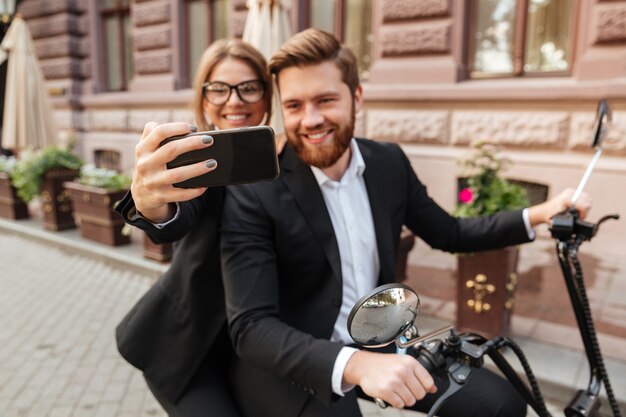 屋外のモダンなバイクに座っている陽気なスタイリッシュなカップル