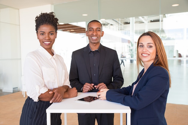 Free photo cheerful successful team of three posing in office hallway