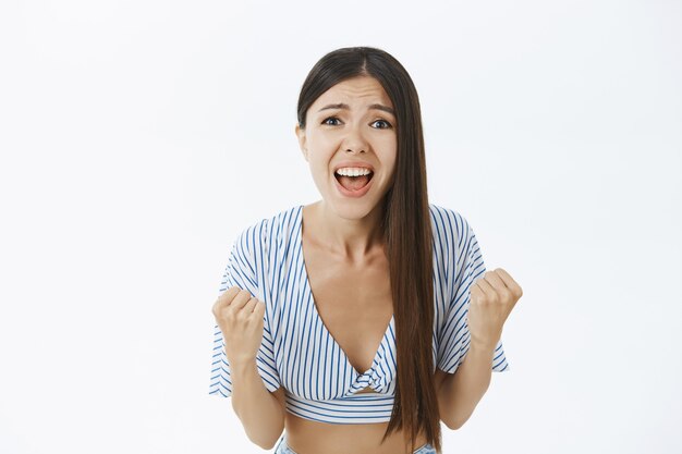 Cheerful supportive and excited female fan in cropped striped blouse clenching fists