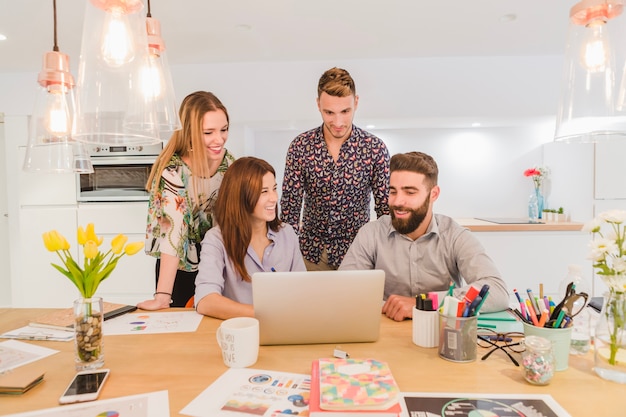 Cheerful team of workers with laptop 