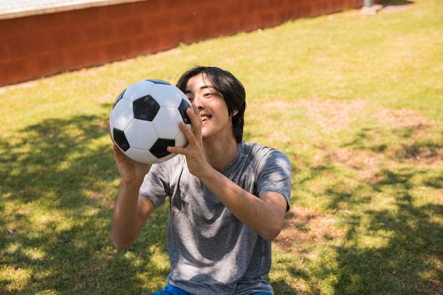 陽気な10代のアジアの学生がサッカーボールを引く