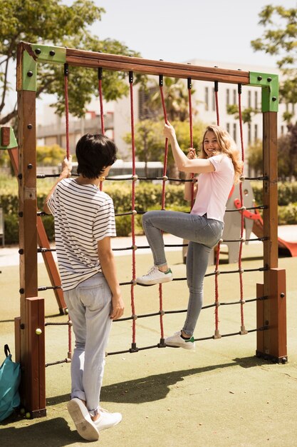 Free Photo cheerful teen friends on climbing net on playground 