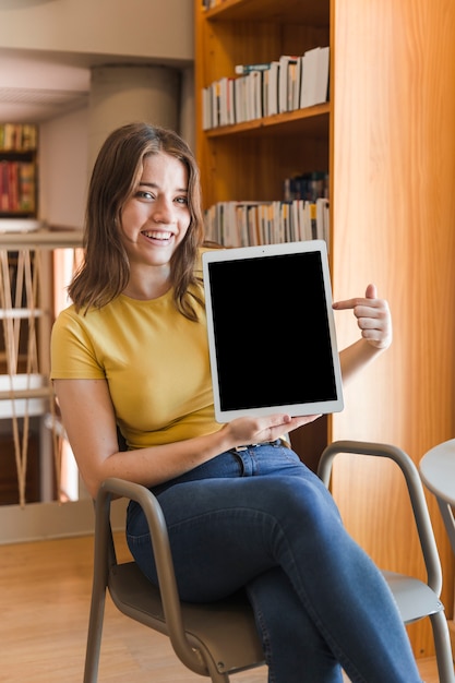 Free photo cheerful teen girl pointing at tablet