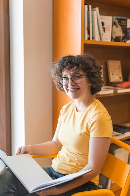 Foto gratuita ragazza teenager allegra con il libro aperto