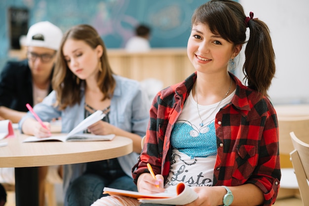 Cheerful teen student girl at table