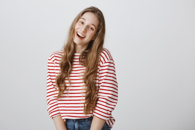 Free photo cheerful teenage girl smiling lovely over grey wall