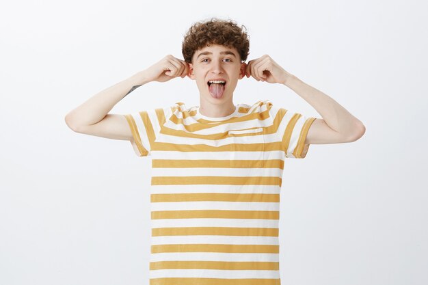 Cheerful teenage guy posing against the white wall