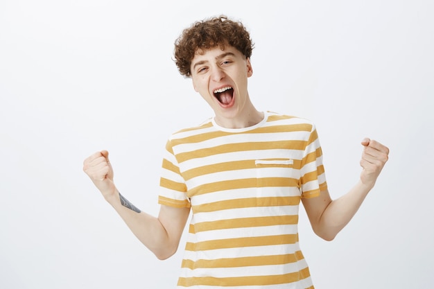 Cheerful teenage guy posing against the white wall