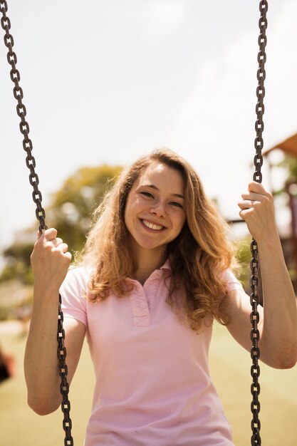 Cheerful teenage woman on swings 