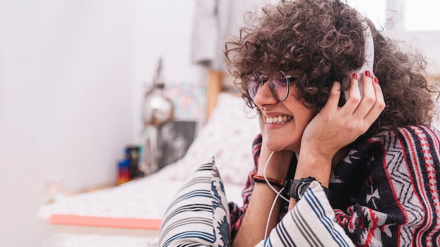 Foto gratuita adolescente allegro che ascolta la musica a letto