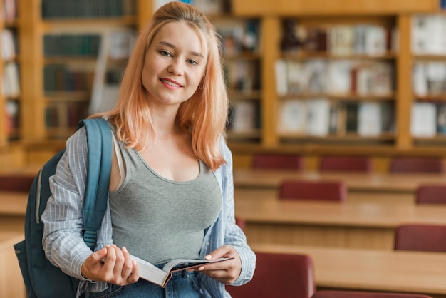 Cheerful teenager near library tables