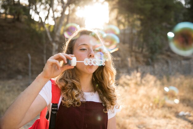 Веселый подросток играет с пузырьками в природе