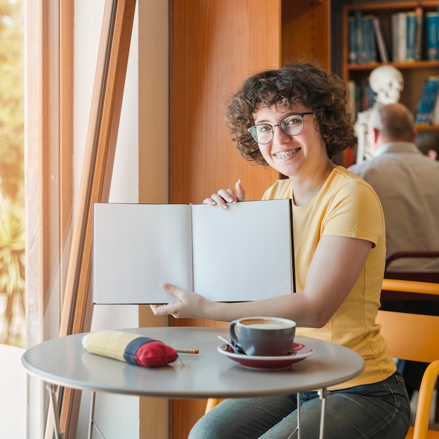 Free photo cheerful teenager showing opened notepad