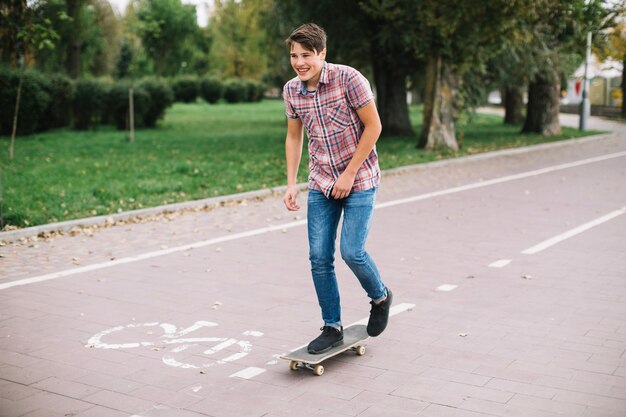 Cheerful teenager skateboarding near bike lane