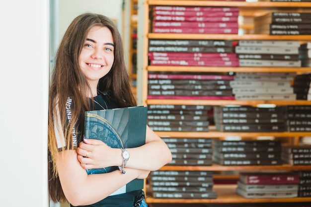 Foto gratuita adolescente allegro con il libro in biblioteca