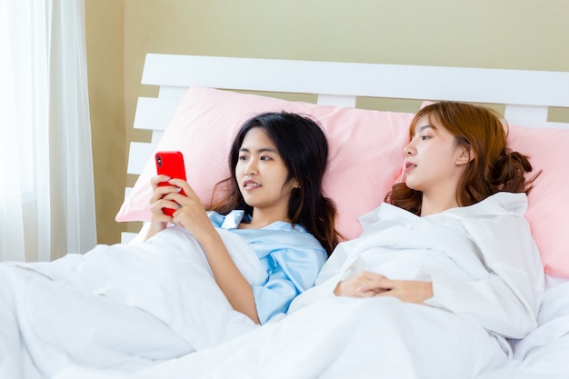 陽気な10代女性がベッドでスマートフォンselfieを使用します。