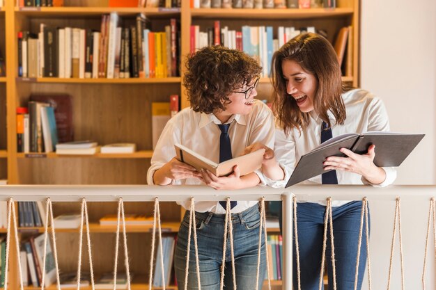 Cheerful teenagers with books in library
