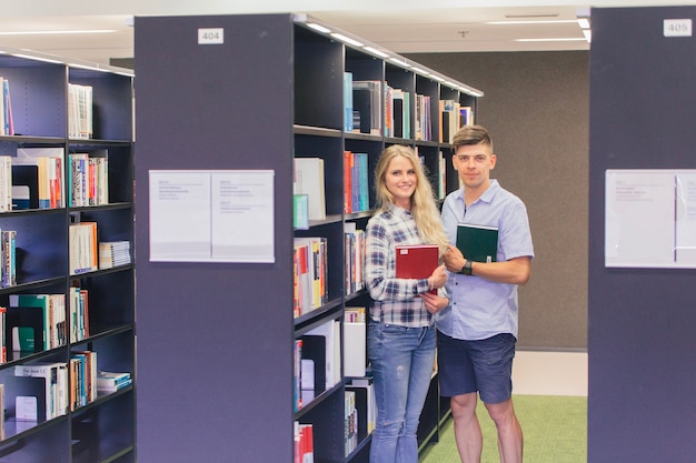 Cheerful teens with books in library