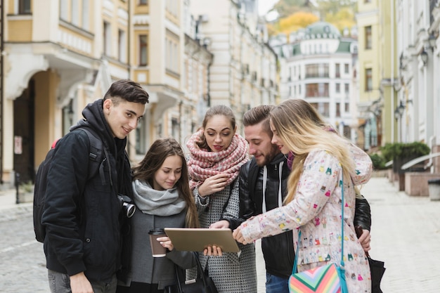 Free photo cheerful tourists with tablet on street