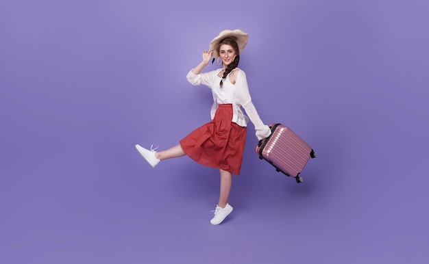 Cheerful traveler tourist woman in summer clothes hat jumping running hold suitcase