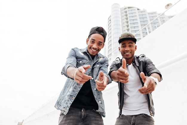 Cheerful two young african men friends pointing.