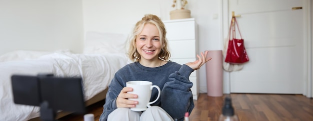 Free photo cheerful woman beauty blogger records lifestyle vlog on digital camera talks casually tells a story